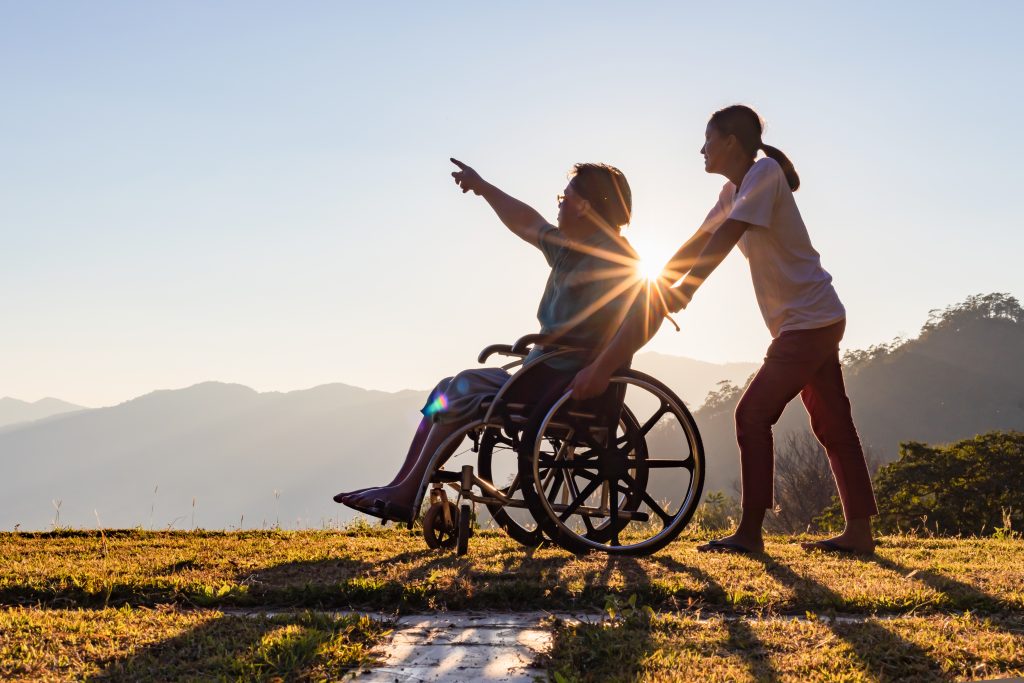 Disabled,Handicapped,Young,Man,In,Wheelchair,Walking,With,His,Care